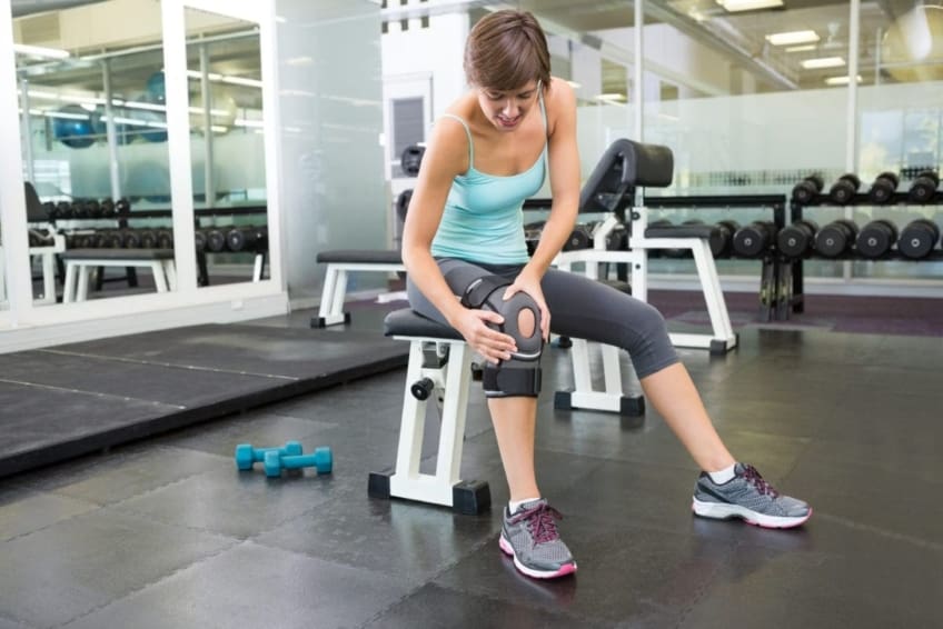 Fit woman wearing a knee brace in a gym